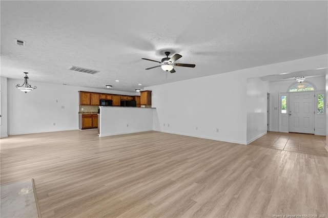 705 Fairfield Cir, Raeford, NC 28376 - unfurnished living room with ceiling fan, a textured ceiling, light wood-style floors, and baseboards
