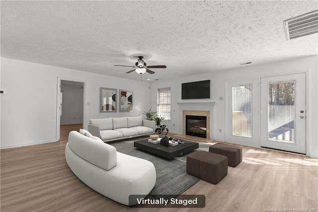705 Fairfield Cir, Raeford, NC 28376 - living room featuring wood finished floors, a textured ceiling, a ceiling fan, a glass covered fireplace, and baseboards