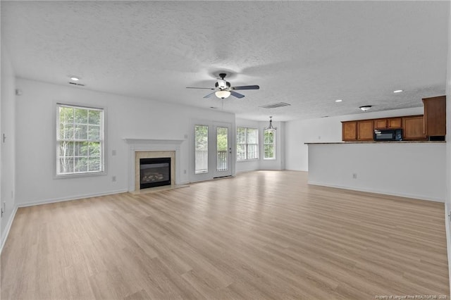 705 Fairfield Cir, Raeford, NC 28376 - unfurnished living room featuring light wood finished floors, a ceiling fan, plenty of natural light, a fireplace, and a textured ceiling