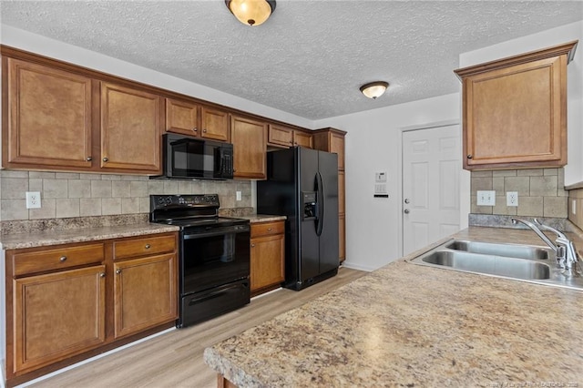 705 Fairfield Cir, Raeford, NC 28376 - kitchen featuring black appliances, light wood-style floors, a sink, brown cabinetry, and backsplash