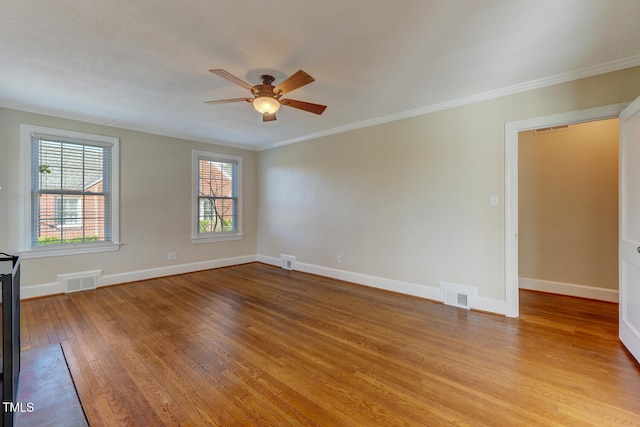 spare room with crown molding, light wood finished floors, a ceiling fan, and visible vents
