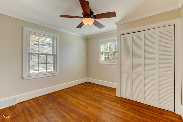 unfurnished bedroom featuring crown molding, light wood-style floors, a closet, visible vents, and baseboards