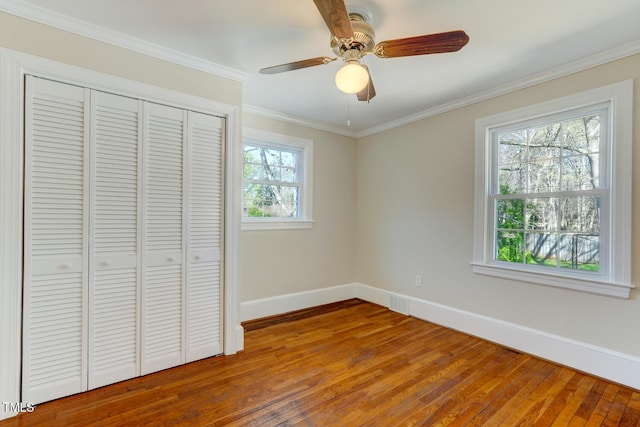 unfurnished bedroom featuring a closet, baseboards, ornamental molding, a ceiling fan, and hardwood / wood-style floors