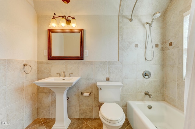 full bath with bathing tub / shower combination, a wainscoted wall, toilet, tile walls, and tile patterned floors