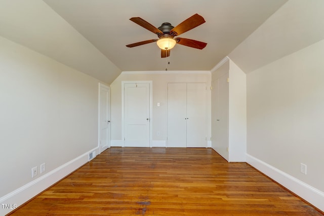 unfurnished bedroom featuring lofted ceiling, baseboards, visible vents, ceiling fan, and wood finished floors