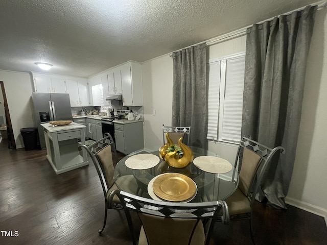 dining area with a textured ceiling, baseboards, and dark wood finished floors