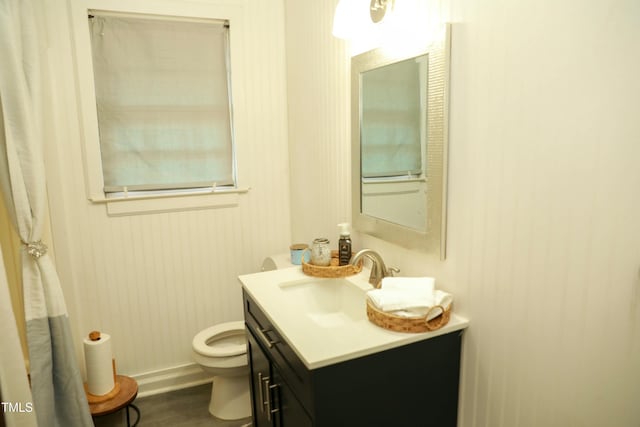 bathroom with toilet, wood finished floors, vanity, and baseboards