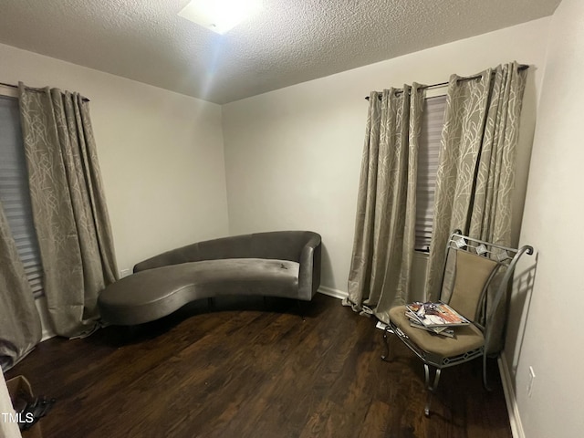 living area featuring a textured ceiling, wood finished floors, and baseboards