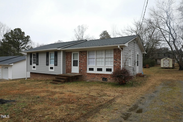 view of front of property featuring roof with shingles, a front yard, brick siding, and an outbuilding