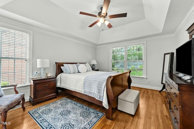 bedroom featuring baseboards, wood finished floors, a raised ceiling, and ceiling fan