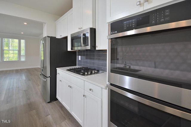 1020 Kentlands Dr, Durham, NC 27713 - kitchen with stainless steel appliances, light wood-style flooring, decorative backsplash, and white cabinetry