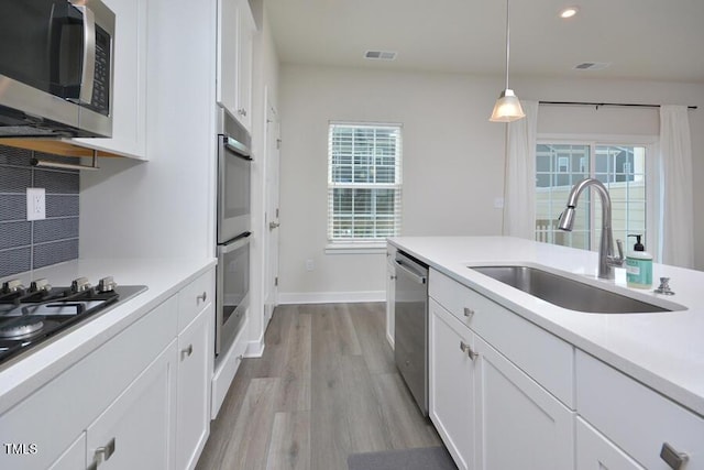 1020 Kentlands Dr, Durham, NC 27713 - kitchen with stainless steel appliances, visible vents, a sink, light wood-type flooring, and tasteful backsplash