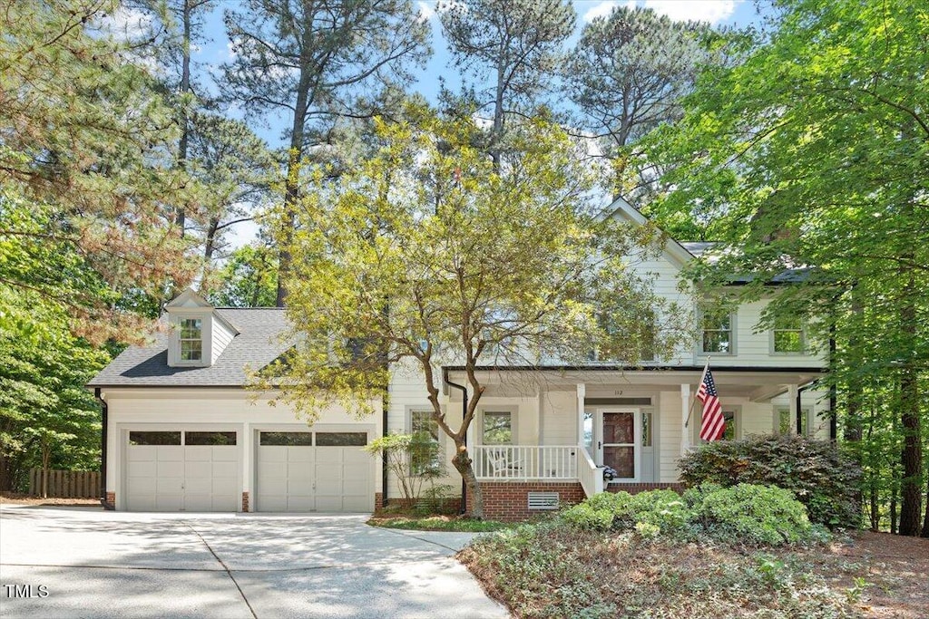 view of front of house featuring fence, covered porch, an attached garage, concrete driveway, and roof with shingles