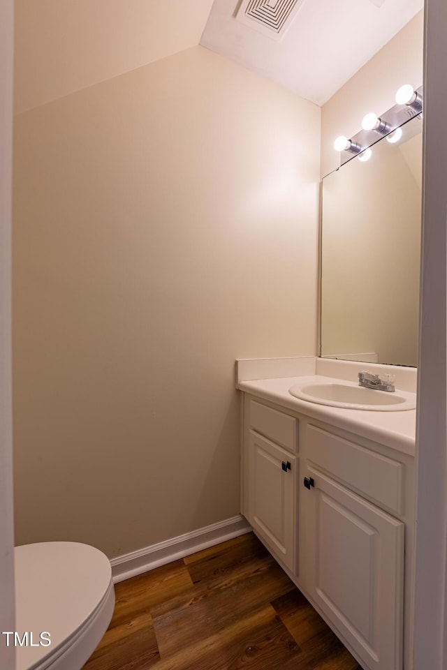 5209 Echo Ridge Rd, Raleigh, NC 27612 - half bathroom with vanity, wood finished floors, toilet, and vaulted ceiling