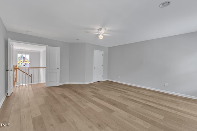 spare room featuring light wood-style floors, baseboards, and ceiling fan with notable chandelier