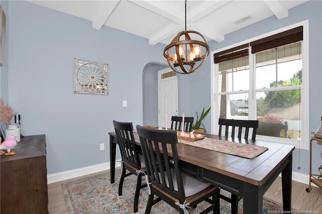 dining space with arched walkways, a chandelier, beam ceiling, baseboards, and light wood finished floors