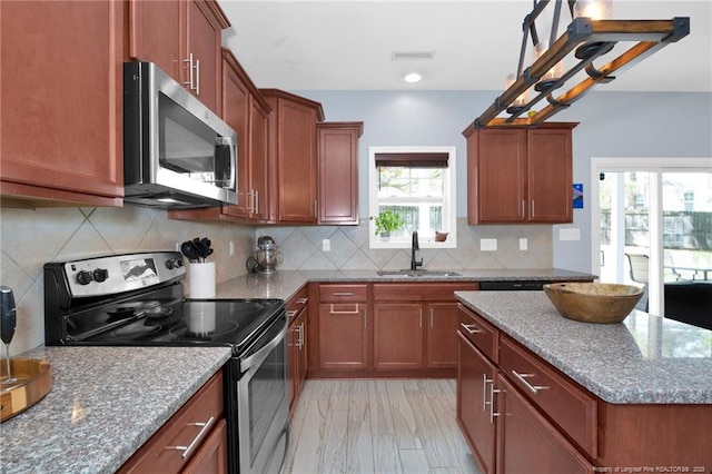 kitchen with stainless steel appliances, a sink, stone counters, backsplash, and a kitchen island
