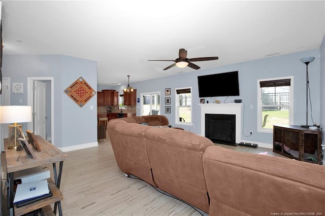 living room featuring ceiling fan, healthy amount of natural light, light wood-style flooring, and baseboards