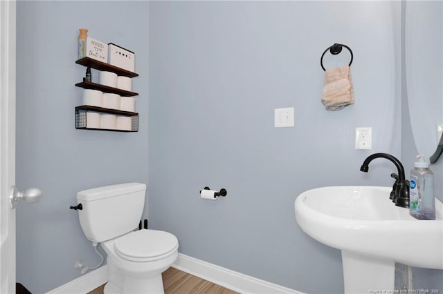 bathroom with baseboards, a sink, toilet, and wood finished floors