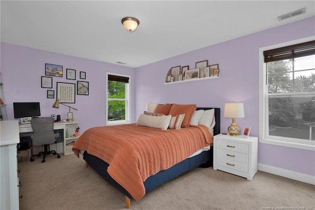 bedroom with light colored carpet, a desk, and baseboards