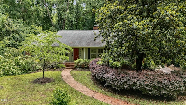 view of front of house featuring a front yard, a chimney, and roof with shingles