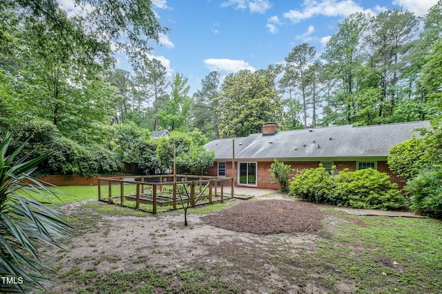 rear view of property with a garden, brick siding, and a chimney