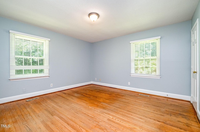 unfurnished room featuring plenty of natural light, baseboards, and wood finished floors