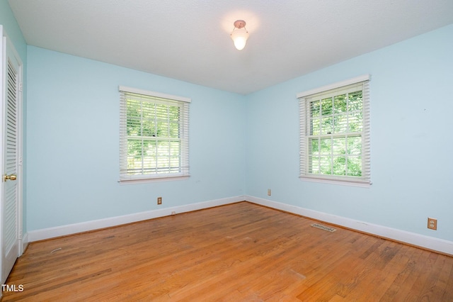 empty room featuring plenty of natural light, light wood-type flooring, and baseboards