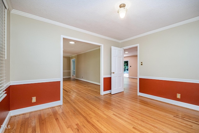 spare room with light wood-style flooring, baseboards, a textured ceiling, and crown molding