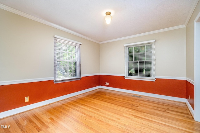 unfurnished room featuring wood finished floors, baseboards, and crown molding