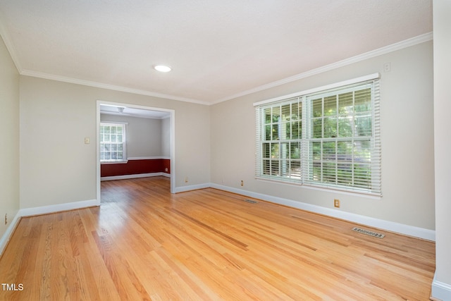 spare room with wood finished floors, baseboards, and crown molding