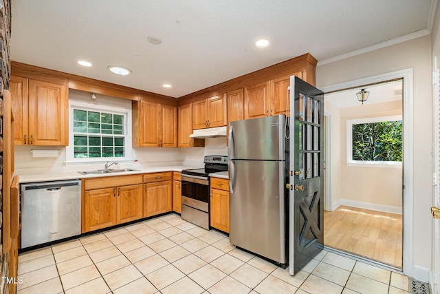 kitchen with stainless steel appliances, a sink, light countertops, light tile patterned flooring, and plenty of natural light