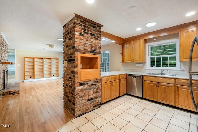kitchen featuring dishwasher, a sink, light countertops, a fireplace, and light wood finished floors