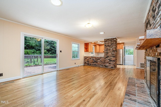 unfurnished living room with ornamental molding, light wood finished floors, baseboards, a fireplace, and recessed lighting
