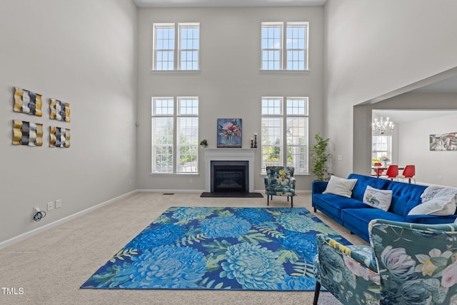 316 Hilliard Forest Dr, Cary, NC 27519 - carpeted living area with a glass covered fireplace, a healthy amount of sunlight, a notable chandelier, and a high ceiling