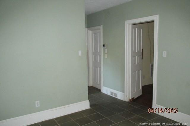 203 W 16th St, Lumberton, NC 28358 - empty room with dark tile patterned flooring and baseboards