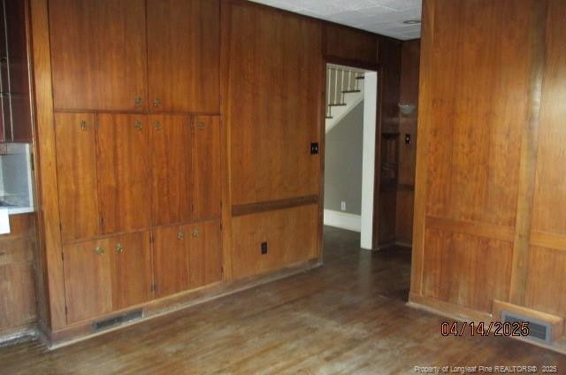 203 W 16th St, Lumberton, NC 28358 - spare room featuring visible vents, stairs, wood finished floors, and wood walls
