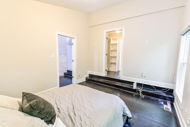 6409 Lakeland Dr, Raleigh, NC 27612 - bedroom featuring wood finished floors, multiple windows, baseboards, and a walk in closet