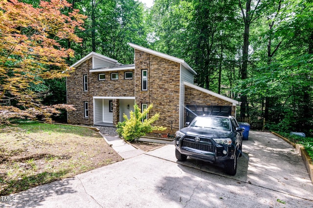 6409 Lakeland Dr, Raleigh, NC 27612 - mid-century modern home with stone siding, a garage, a porch, concrete driveway, and a view of trees