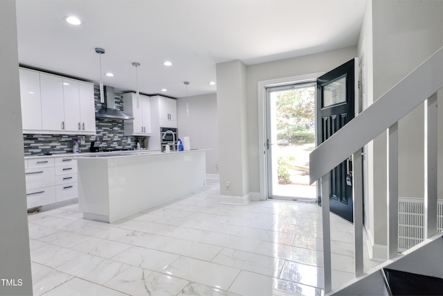6409 Lakeland Dr, Raleigh, NC 27612 - kitchen featuring wall chimney range hood, decorative backsplash, light marble finish floors, white cabinetry, and recessed lighting