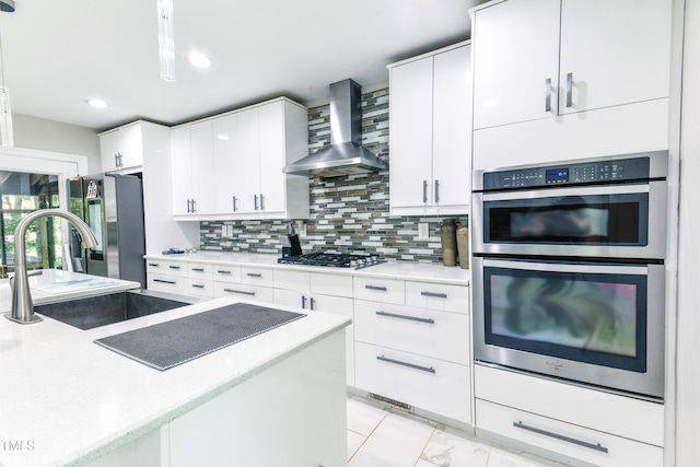 6409 Lakeland Dr, Raleigh, NC 27612 - kitchen featuring wall chimney range hood, appliances with stainless steel finishes, decorative backsplash, white cabinetry, and a sink