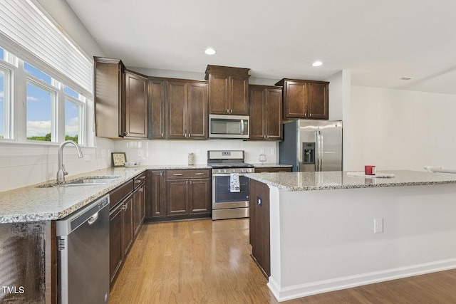 2027 Hayes Ln, Holly Springs, NC 27540 - kitchen with stainless steel appliances, a sink, light wood finished floors, dark brown cabinetry, and recessed lighting