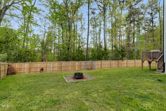 view of yard featuring stairway, a deck, a fenced backyard, and an outdoor fire pit