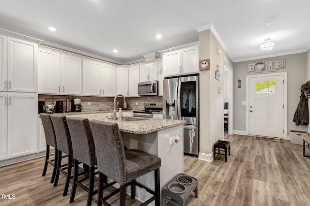 kitchen with tasteful backsplash, a center island with sink, a breakfast bar area, appliances with stainless steel finishes, and a sink