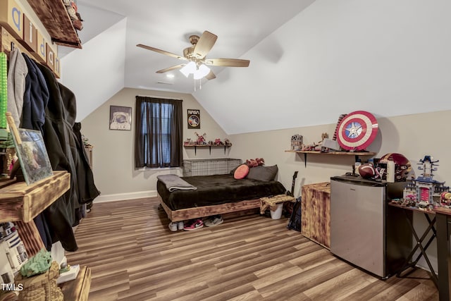 bedroom featuring lofted ceiling, baseboards, light wood-type flooring, freestanding refrigerator, and ceiling fan