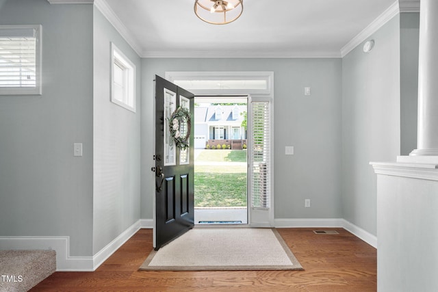 foyer entrance with crown molding, wood finished floors, and visible vents