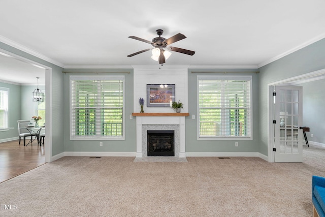 carpeted living room featuring crown molding, a fireplace with flush hearth, baseboards, and ceiling fan