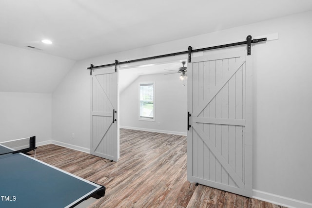 game room featuring visible vents, a barn door, wood finished floors, and vaulted ceiling