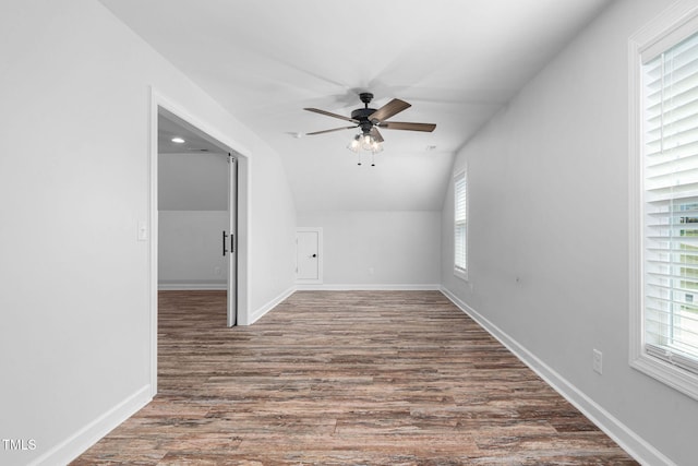 empty room with a ceiling fan, lofted ceiling, wood finished floors, and a healthy amount of sunlight