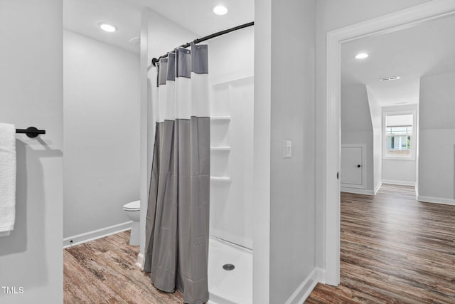 full bathroom featuring wood finished floors, toilet, baseboards, recessed lighting, and a shower stall